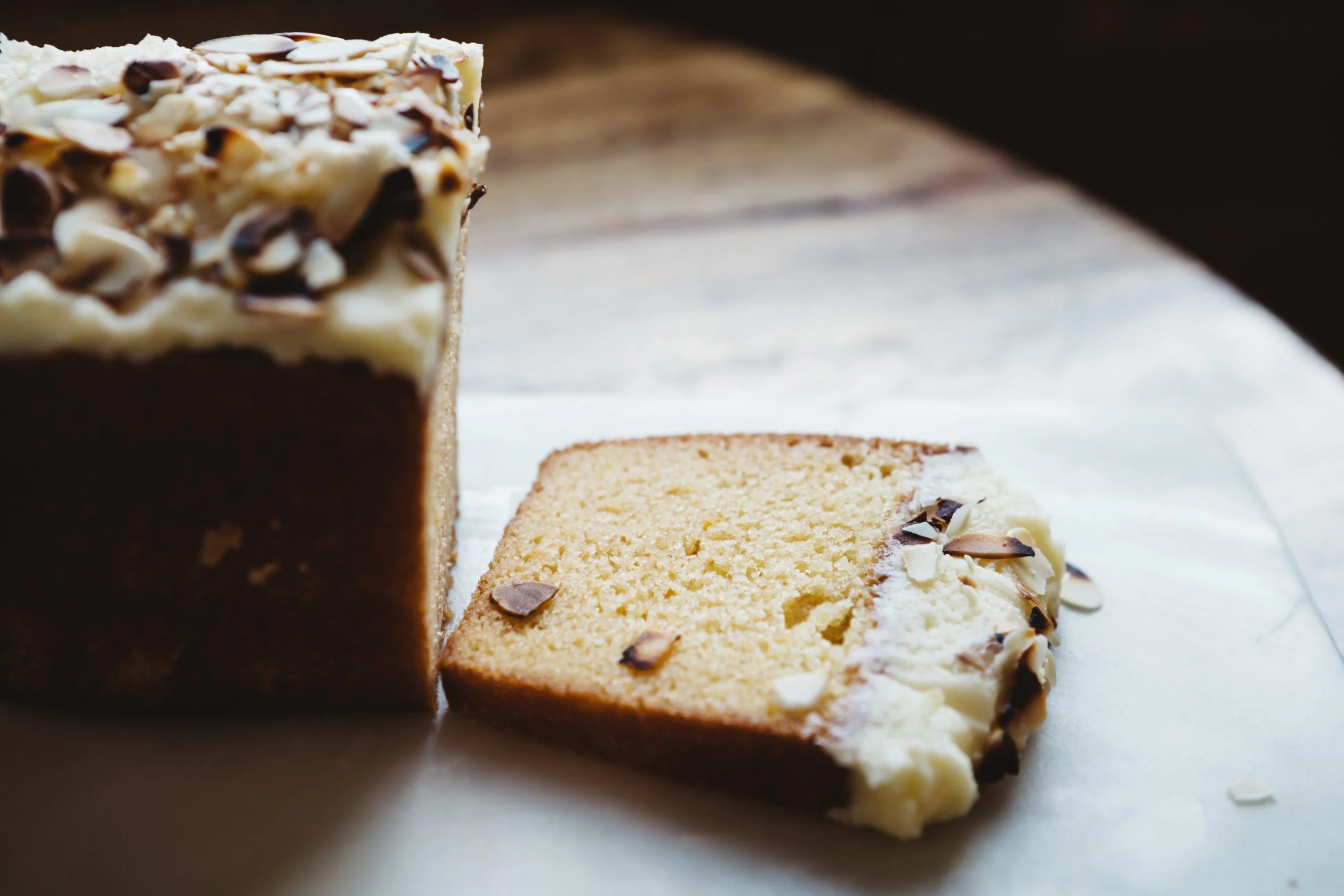 Torta umida glassata alla vaniglia, ricoperta di mandorle.